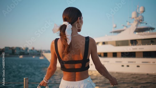 Tanned woman posing pier with luxury yacht close up. Girl standing on embankment photo