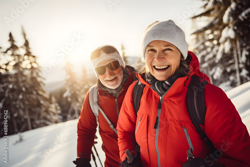 An elderly couple hiking through a snow-covered landscape and having a lot of fun.