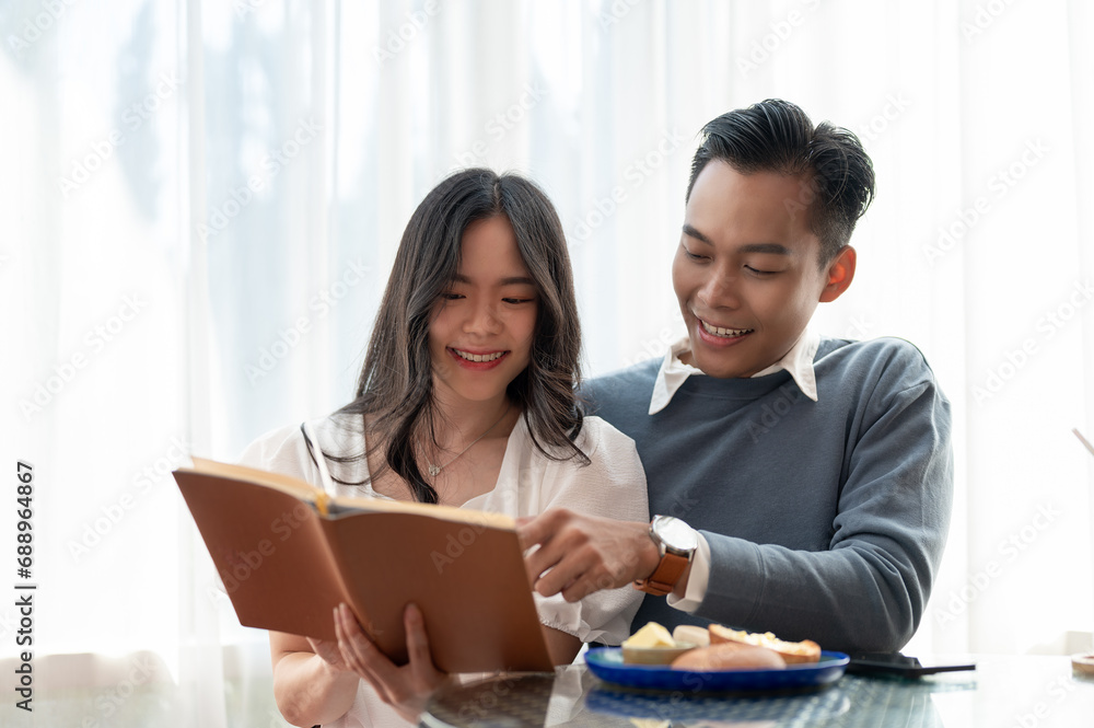 Young beautiful adorable Asian couple sharing their free time together, reading books in a cute cafe Young beautiful adorable Asian couple sharing their free time together, reading books in a cute cafe