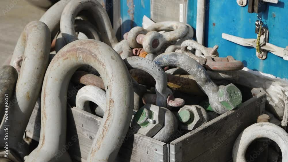 Heavy navy stainless steel chain and its parts neatly arranged in a wooden box on the dock, ready for use Heavy navy stainless steel chain and its parts neatly arranged in a wooden box on the dock, ready for use