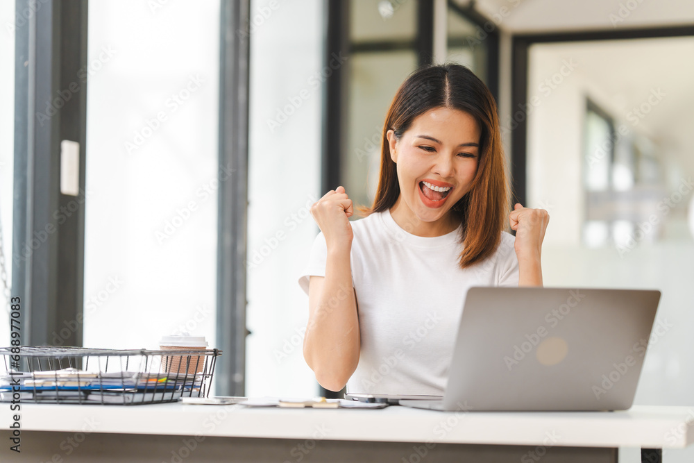 Cheerful Asian woman confidently uses mobile phone, tablet with laptop and notebooks on the desk in a bright office. Cheerful Asian woman confidently uses mobile phone, tablet with laptop and notebooks on the desk in a bright office.