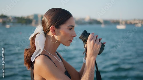 Tourist woman looking binoculars at ocean shore close up. Gorgeous girl smiling photo