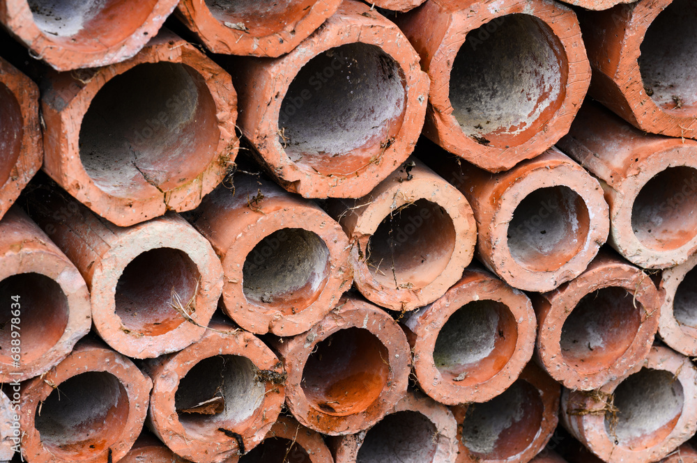 Drainage old clay pipes for sewage stacked in a texture with holes