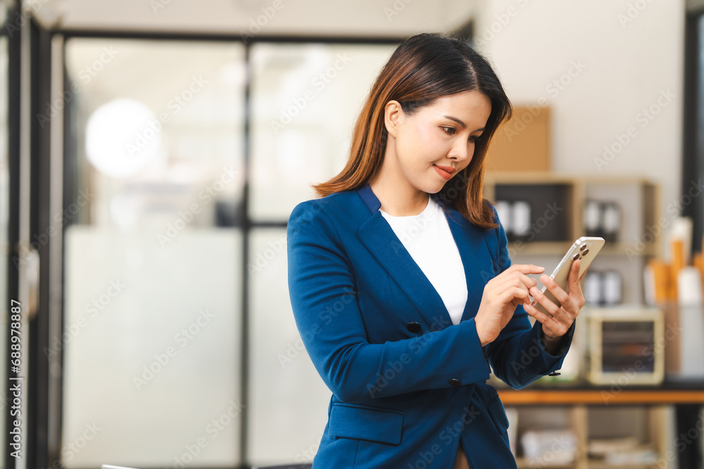 Happy attractive middle aged Asian people advertising manager business woman in formal suit smiles while using laptop, tablet, mobile phone, with laptop and coffee on desk. Happy attractive middle aged Asian people advertising manager business woman in formal suit smiles while using laptop, tablet, mobile phone, with laptop and coffee on desk.