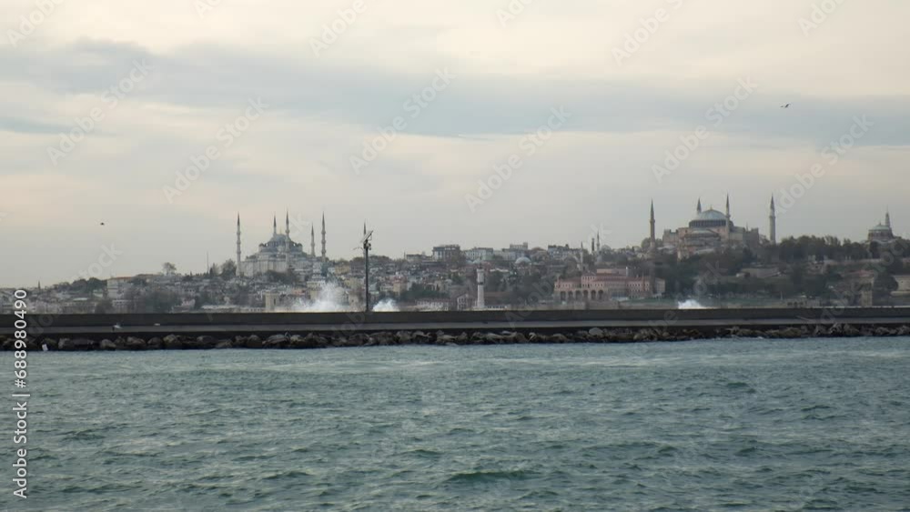 Big waves are hitting and splashing over the jetty in Istanbul in slow motion. The Hagia Sophia and The Blue Mosque are visible at the background. Big waves are hitting and splashing over the jetty in Istanbul in slow motion. The Hagia Sophia and The Blue Mosque are visible at the background.