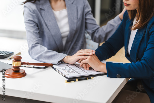 Foto Two middle aged and young Asian lawyer in a formal suit consoles a client during a legal consultation, with a gavel and documents on the table