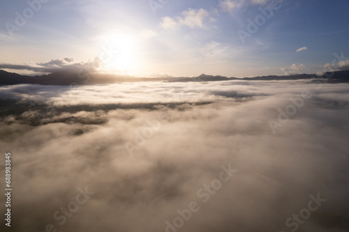 Aerial view of flowing fog waves on mountain tropical rainforest,Bird eye view image over the clouds Amazing nature background with clouds and mountain peaks in Thailand