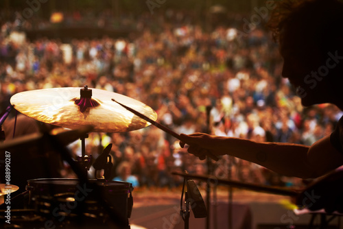 Drummer, music and crowd at stage, concert or musician in performance at festival or event with fans. Playing, rock or man on drums in a metal band with audience listening to beat, sound or show photo
