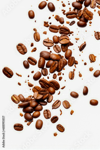 Pile of coffee beans on white surface with few scattered around.