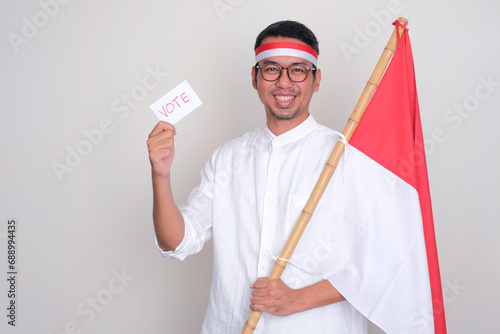Indonesian man smiling confident while holding presidential election vote card photo
