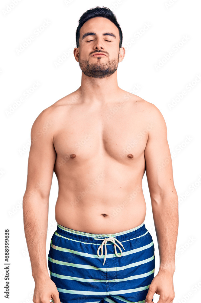 Young handsome man wearing swimwear looking at the camera blowing a kiss on air being lovely and sexy. love expression. Young handsome man wearing swimwear looking at the camera blowing a kiss on air being lovely and sexy. love expression.