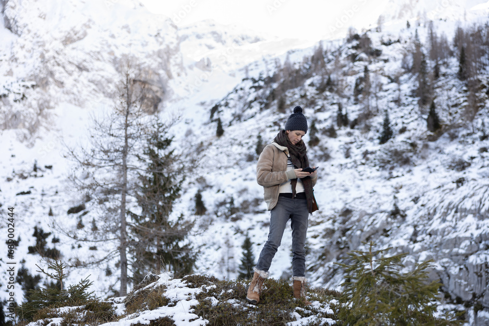 Adult Woman Checking Cell Phone Hiking in Cold Snowy Winter Mountain Wilderness