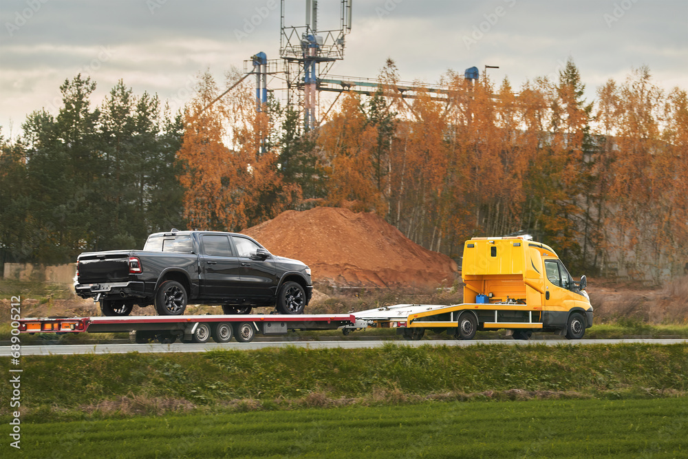 Tow truck with a broken pickup truck on the interstate highway. Tow