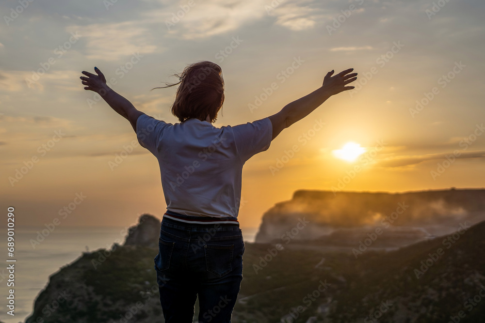 Happy woman on sunset in mountains. Woman standing with her back on the sunset in nature in summer with open hands. Silhouette. Happy woman on sunset in mountains. Woman standing with her back on the sunset in nature in summer with open hands. Silhouette.