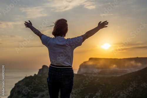 Happy woman on sunset in mountains. Woman standing with her back on the sunset in nature in summer with open hands. Silhouette.