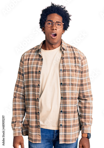 Handsome african american man with afro hair wearing casual clothes and glasses in shock face, looking skeptical and sarcastic, surprised with open mouth
