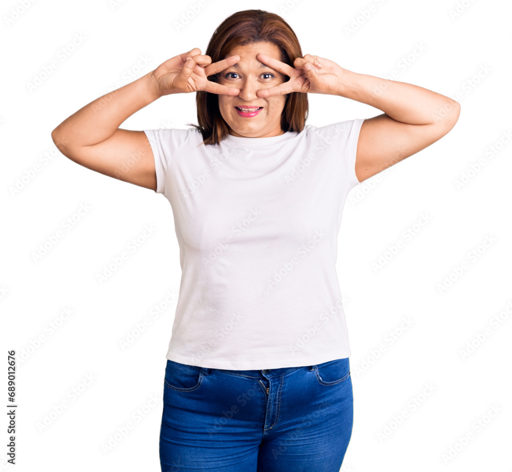 Middle age latin woman wearing casual white tshirt doing peace symbol with fingers over face, smiling cheerful showing victory Middle age latin woman wearing casual white tshirt doing peace symbol with fingers over face, smiling cheerful showing victory