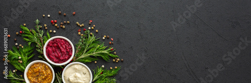Different types of sauces in bowls with seasonings banner, rosemary and dill, thyme and and peppercorns, top view, copy space photo
