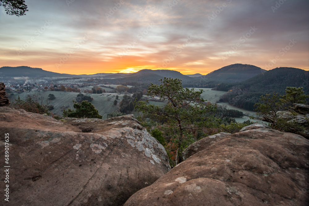 Hilly landscape shot on a sandstone rock in the forest. Cold morning mood at sunrise at a viewpoint. Winter morning in Palatinate Forest, Germany