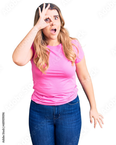 Young caucasian woman wearing sportswear doing ok gesture shocked with surprised face, eye looking through fingers. unbelieving expression.