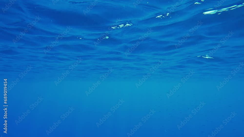 Blue water surface with sun rays on a sunny day, Natural underwater background Blue water surface with sun rays on a sunny day, Natural underwater background
