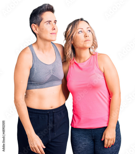 Couple of women wearing sportswear smiling looking to the side and staring away thinking. © Krakenimages.com