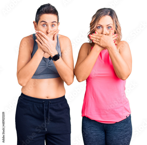 Couple of women wearing sportswear shocked covering mouth with hands for mistake. secret concept.