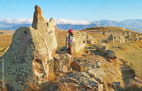 Female Traveler Visiting the Prehistoric Archaeological Site of Carahunge or Armenian Stonehenge in Syunik Province of Armenia photo