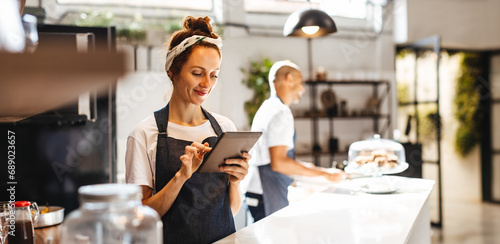 Waitress using digital tablet to view and manage orders in a coffee shop photo