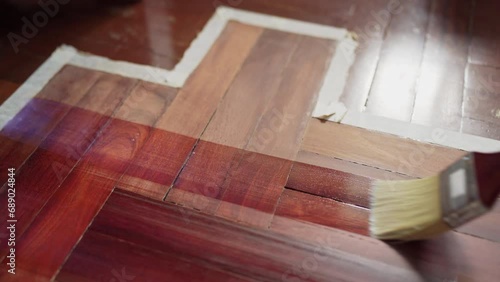 Apply clear wood stain on wooden floor with brush photo