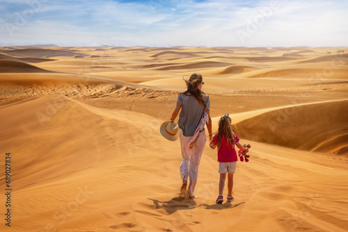 A mother and daughter exploring the sandy desert dunes near Dubai, Middle East