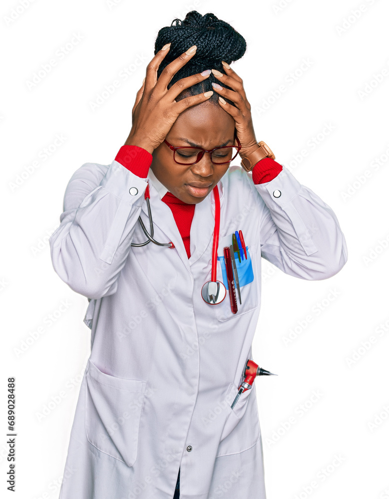 Young african american woman wearing doctor uniform and stethoscope suffering from headache desperate and stressed because pain and migraine. hands on head.