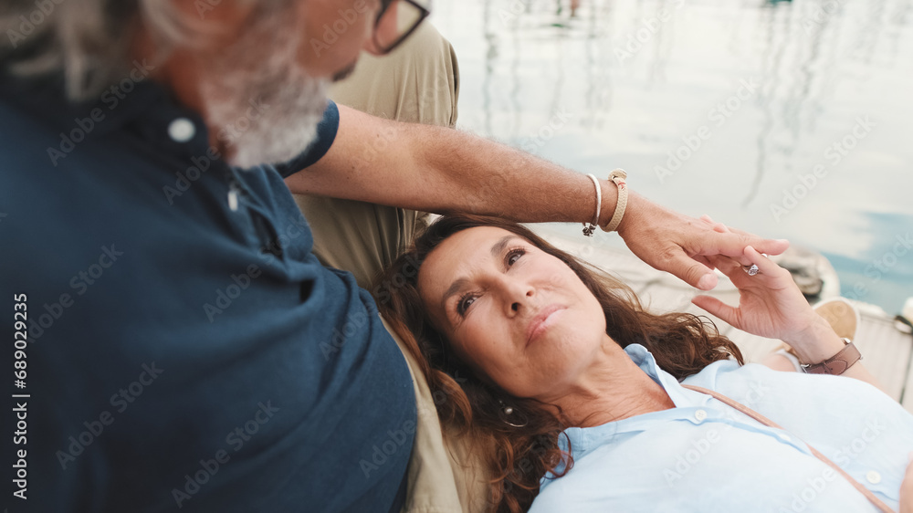 Close up, happy middle aged couple, retired elderly couple enjoy joint outdoor recreation, relax and chat lying on pier Close up, happy middle aged couple, retired elderly couple enjoy joint outdoor recreation, relax and chat lying on pier
