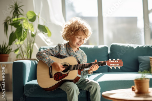 Cute little boy learning to play guitar in living room. Child having fun with music instrument. Art education for kids. photo