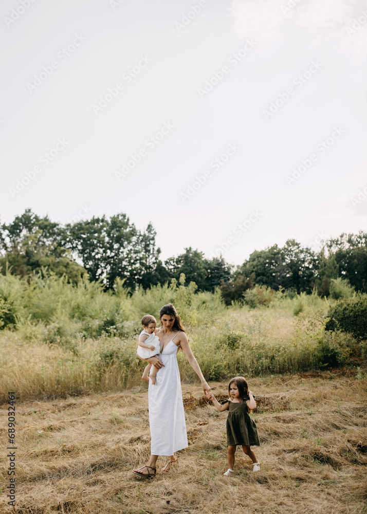 Mother walking with two children, holding hands, in a field on a summer day. Mother walking with two children, holding hands, in a field on a summer day.