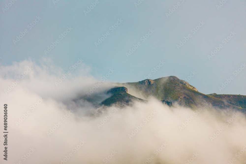 Mountains in the clouds. View of the mountain peak in the fog. Beautiful landscape with high cliffs. Dedegol. Turkey.