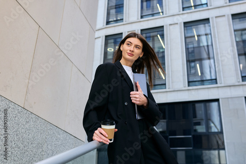 A female office employee is waiting for her colleague standing outside an office building before starting work © makedonski2015