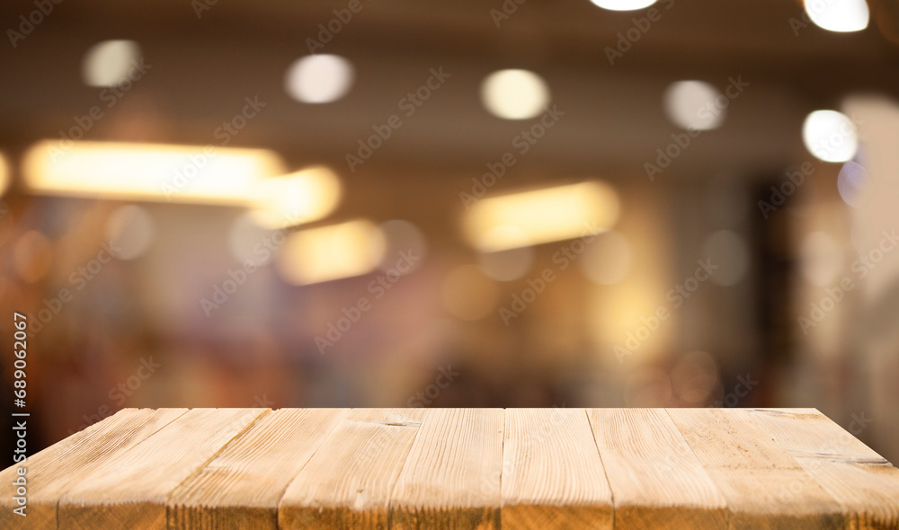 Empty wooden table top on blur light golden bokeh of cafe restaurant, bar in a dark background.