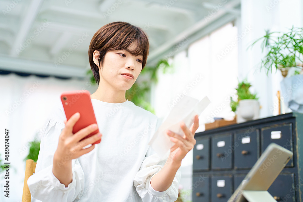 レシートとスマートフォンを手にする若い女性 レシートとスマートフォンを手にする若い女性