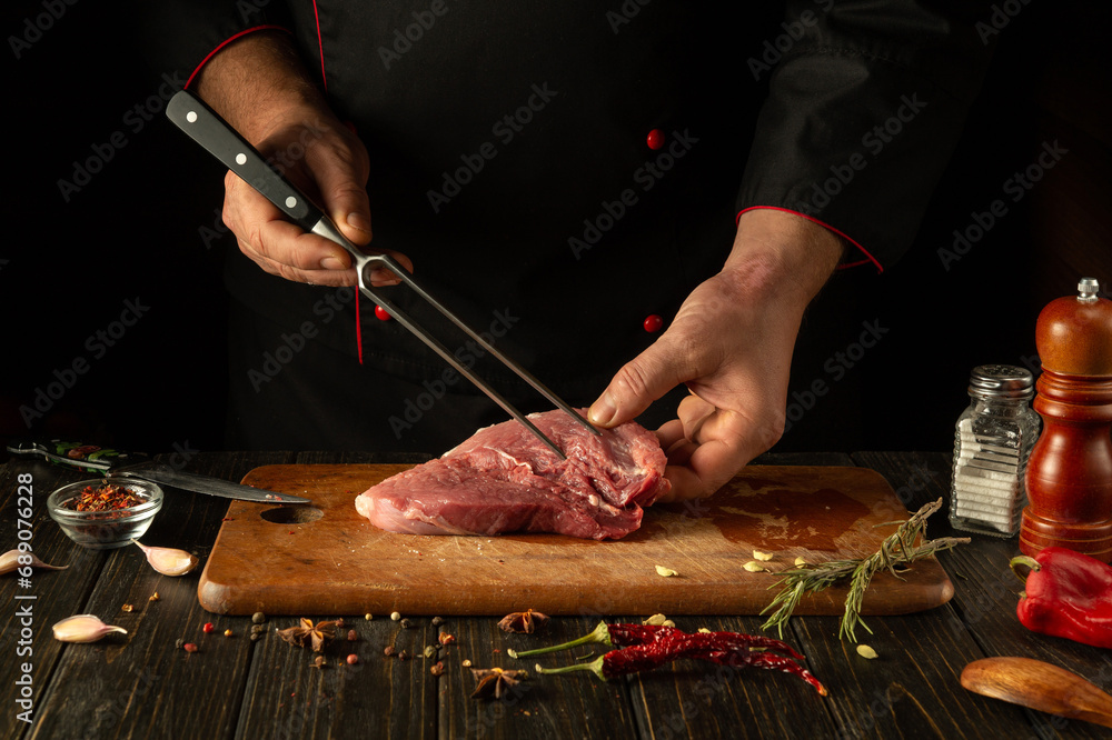 The process of preparing a meat steak by the hands of a chef on a kitchen table with aromatic spices. Cooking juicy and flavorful shish kebab for lunch or dinner