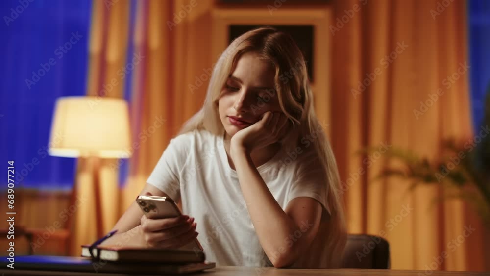 A tired after checking homework young lady teacher holds a smartphone and answers messages from pupils, resting her face on hand. A blonde girl student sends links to hints to exam for a fellow A tired after checking homework young lady teacher holds a smartphone and answers messages from pupils, resting her face on hand. A blonde girl student sends links to hints to exam for a fellow