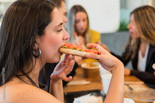 Woman biting bruschetta against friends in cafe