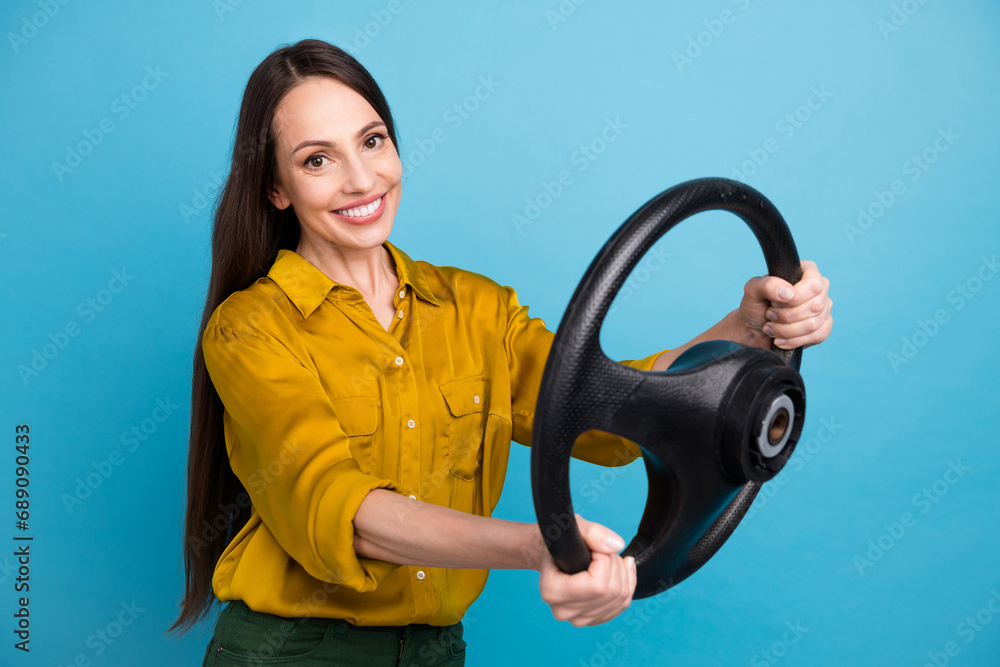 Photo of good mood positive woman dressed yellow shirt driving automobile isolated blue color background Photo of good mood positive woman dressed yellow shirt driving automobile isolated blue color background