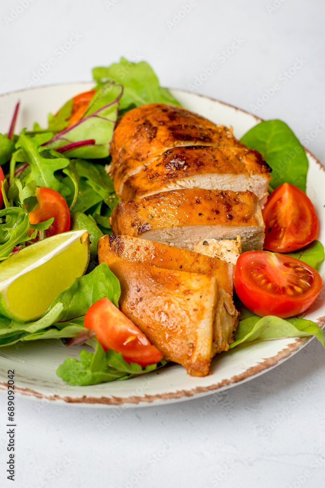 Salad with chicken breast, fillet with lettuce and cherry tomatoes on a plate on a light background, close up Salad with chicken breast, fillet with lettuce and cherry tomatoes on a plate on a light background, close up