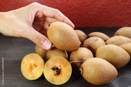 Closeup of Man's Hand Picking a Sapodilla Fruit photo