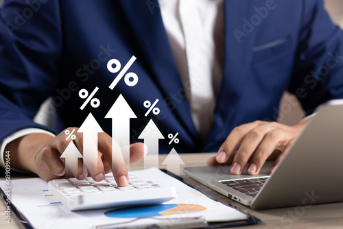 Interest rate concept, Business man using calculator with graph percentage symbol and up arrow, Growth of investments and profits, Dividends and long term investing to win Inflation, Calculate taxes. photo