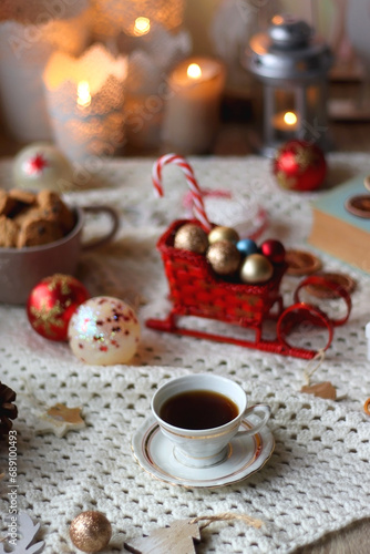 Various colorful Christmas decorations, soft blanket, cup of tea, sweet snacks and lit candles on the table. Cozy Christmas atmosphere at home. Selective focus.