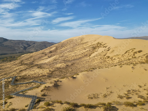 Desert dune in the morning sunlight with blue sky and mountains in the backdrop. Natural background.