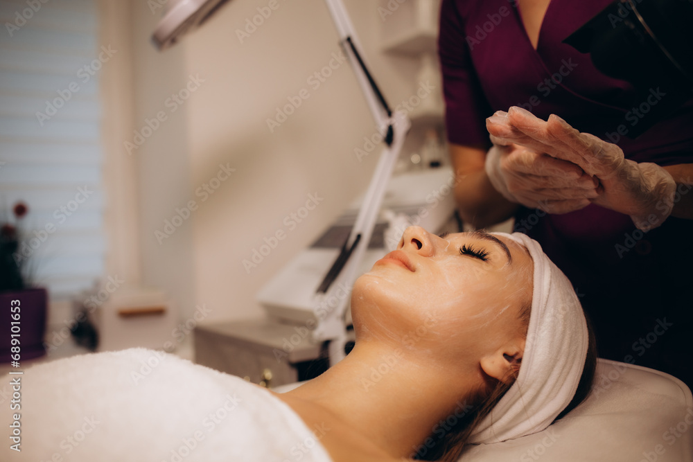 Cosmetologist applying mask on woman's face in spa salon, closeup Cosmetologist applying mask on woman's face in spa salon, closeup