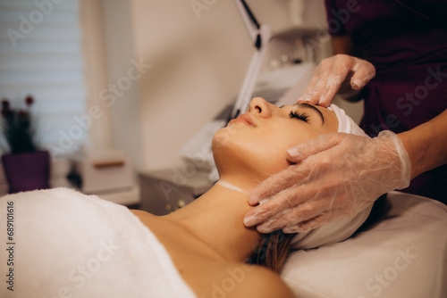 Cosmetologist applying mask on woman's face in spa salon, closeup